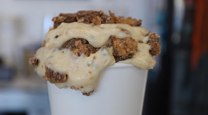 cannoli pudding dessert with cookie crumbles on top in a white cup against a blurred background